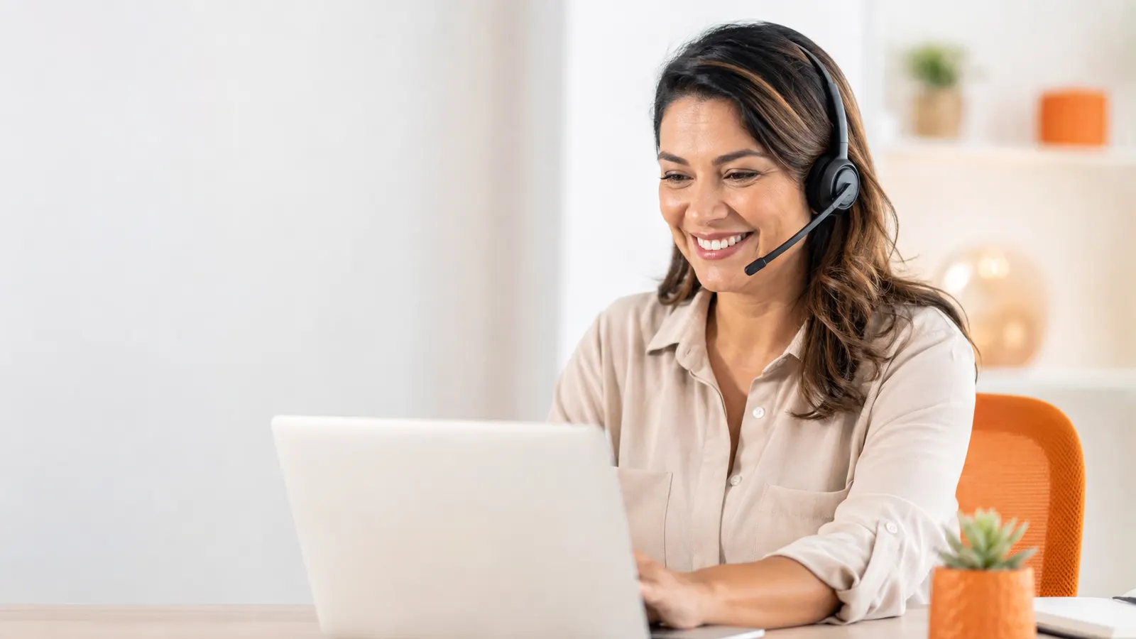 Atendente do YouDesp de fone com microfone, sorrindo enquanto atende no computador